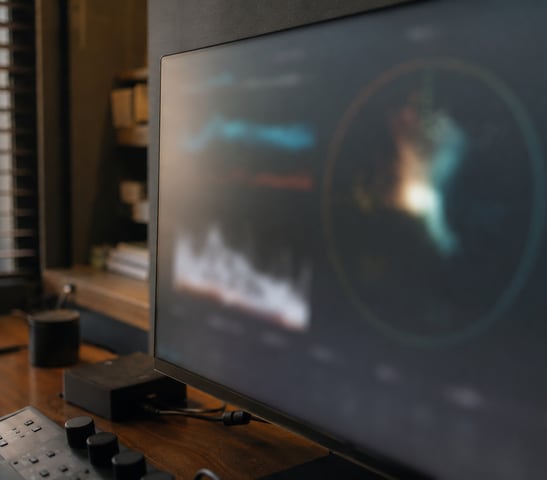 Ultrawide monitor displaying lines of code in a programming editor on a desk with books and headphones.